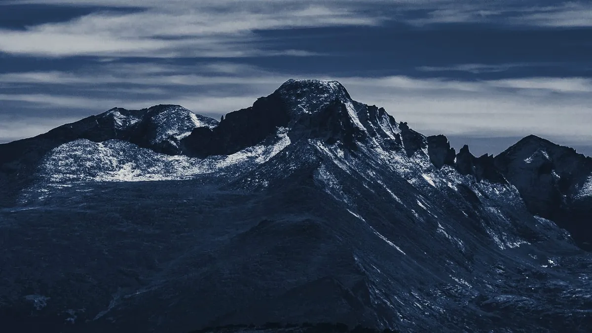 A snow-streaked summit under long bands of cloud